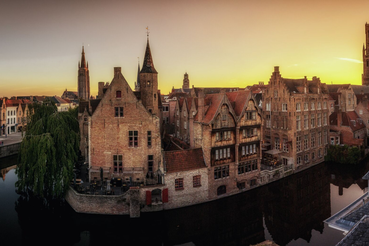Medieval canal town at sunset Sunset over a medieval canal city with brick buildings, church towers, and reflections in calm water.