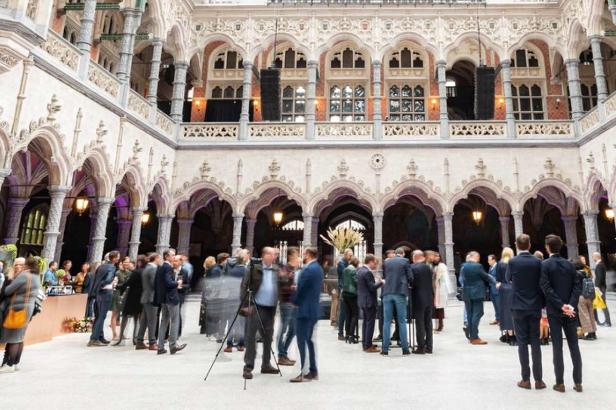 Reception in ornate arched courtyard Crowd mingling at a reception in an ornate arched courtyard with gothic columns and balconies.